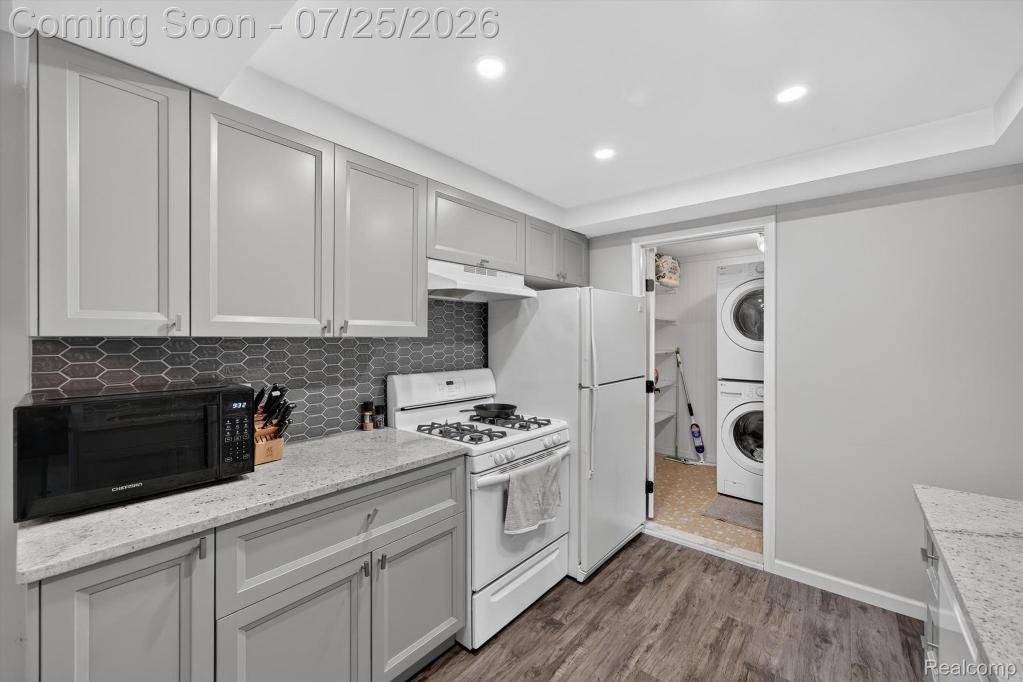 51116 South Foster Road New Baltimore, MI 48047 - Photo 14 of 31 Modern kitchen featuring grey shaker-style cabinetry, light speckled countertops, a dark hexagonal tile backsplash, and wood-finish flooring