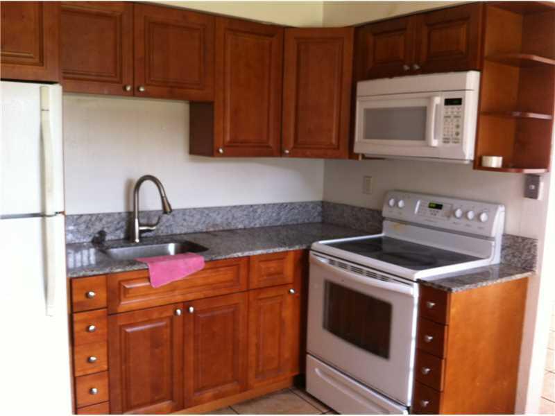 a kitchen with granite countertop a stove top oven microwave and cabinets
