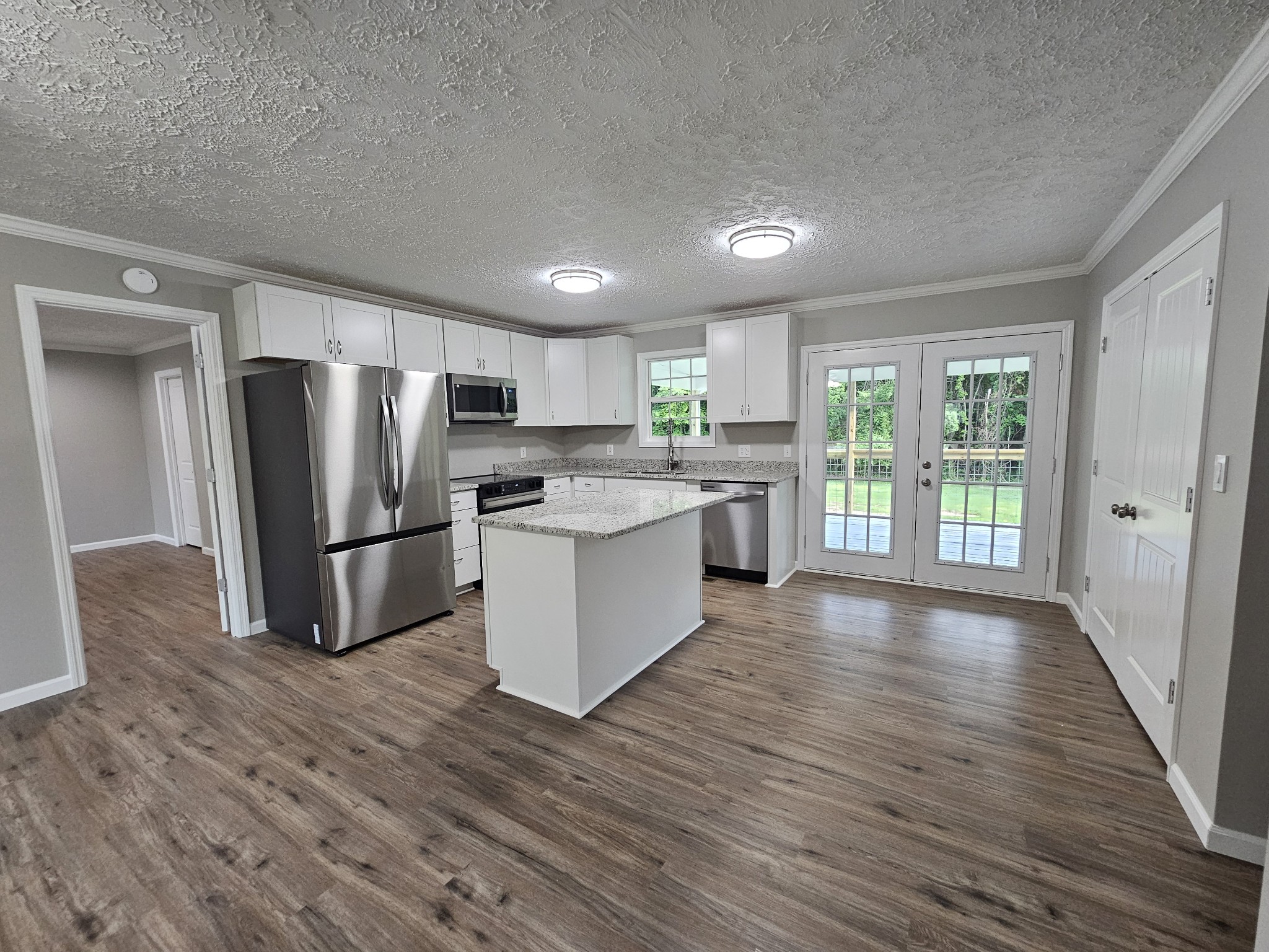 362 Forest Point Road Monteagle, TN 37356 - Photo 26 of 42 a kitchen with stainless steel appliances a refrigerator a wooden floor and white cabinets