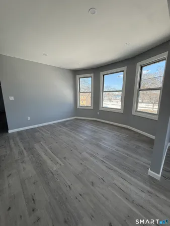 a view of an empty room with wooden floor and window