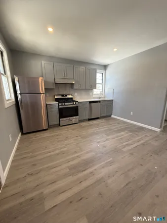 a kitchen with stainless steel appliances granite countertop a refrigerator a stove and a sink