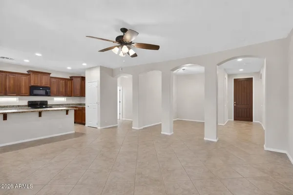 an empty room with a chandelier fan and windows