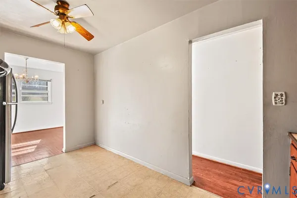 a view of an empty room with chandelier fan
