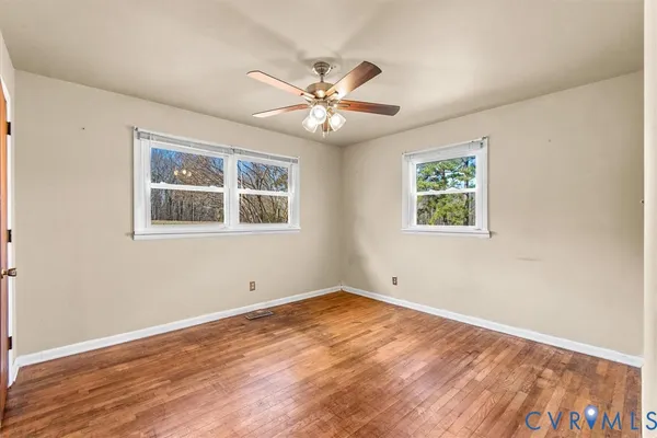 a view of an empty room with window and wooden floor