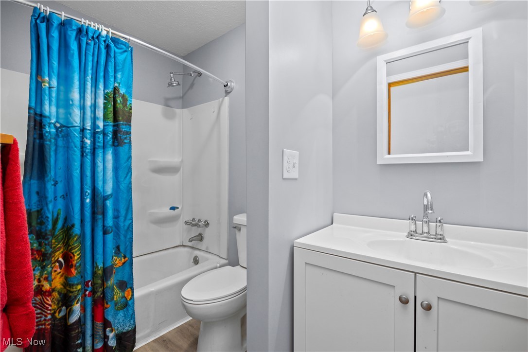 14015 West Lake Road Vermilion, OH 44089 - Photo 39 of 50 Full bathroom with vanity, shower / bath combo, a textured ceiling, and wood finished floors