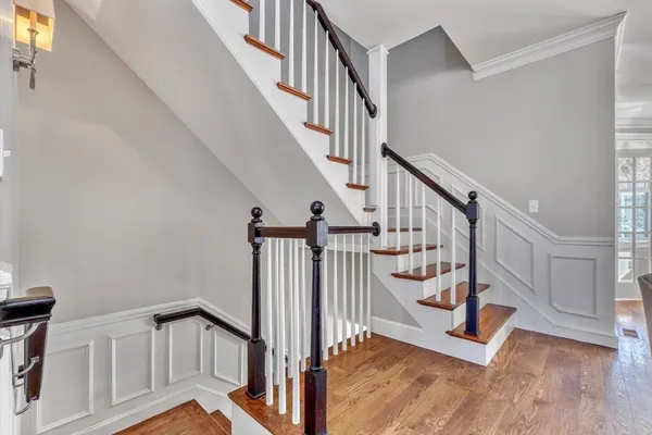 a view of staircase with lots of frames on wall and wooden floor