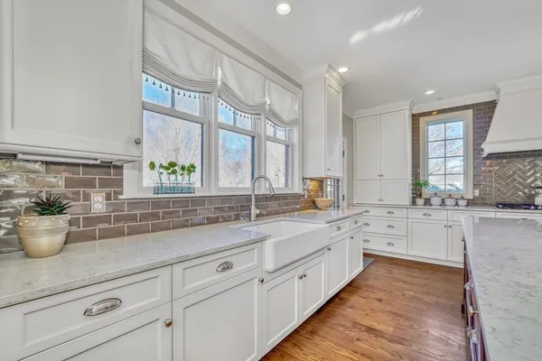 a large white kitchen with stainless steel appliances granite countertop a lot of counter space and a sink