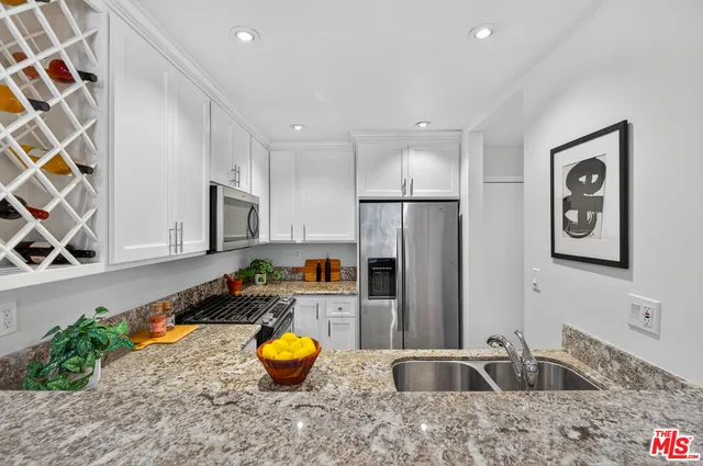 a kitchen with stainless steel appliances a sink a microwave a refrigerator and cabinets