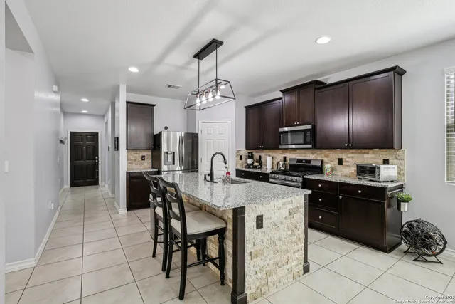 a kitchen with refrigerator a stove and chairs