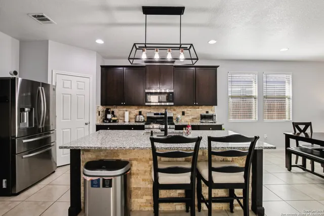 a kitchen with stainless steel appliances granite countertop a sink a stove and a refrigerator