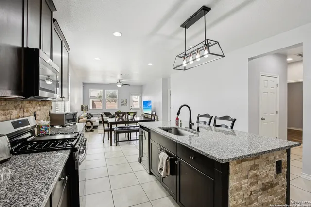 a kitchen with granite countertop a sink a counter top space appliances and cabinets