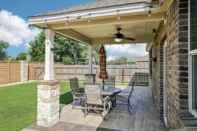 a view of a patio with table and chairs with wooden floor and fence