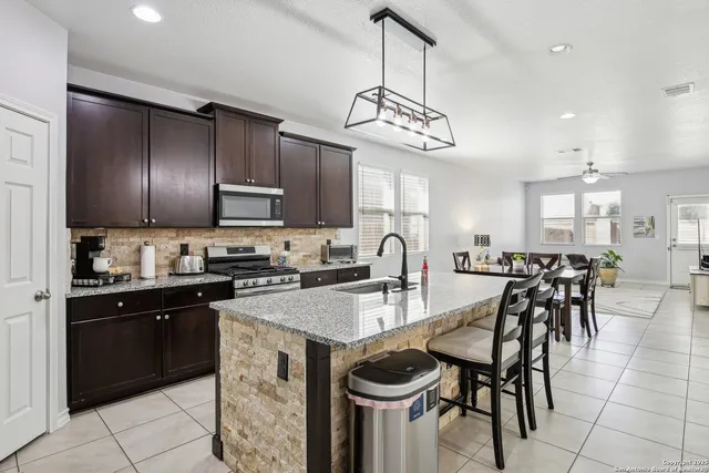 a kitchen with lots of wooden cabinets a sink appliances and dining table