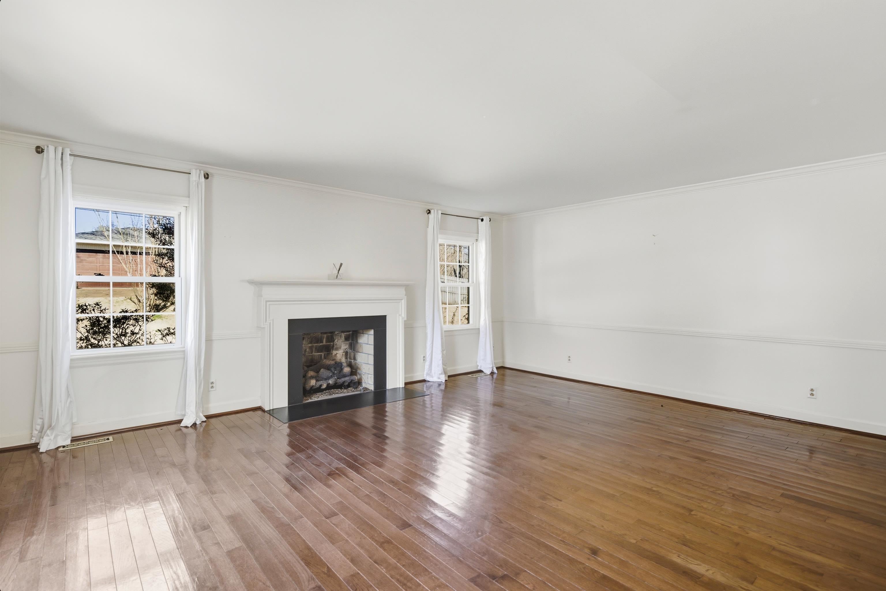 126 Rooks Drive Brownsville, TN 38012 - Photo 6 of 37 an empty room with wooden floor fireplace and windows