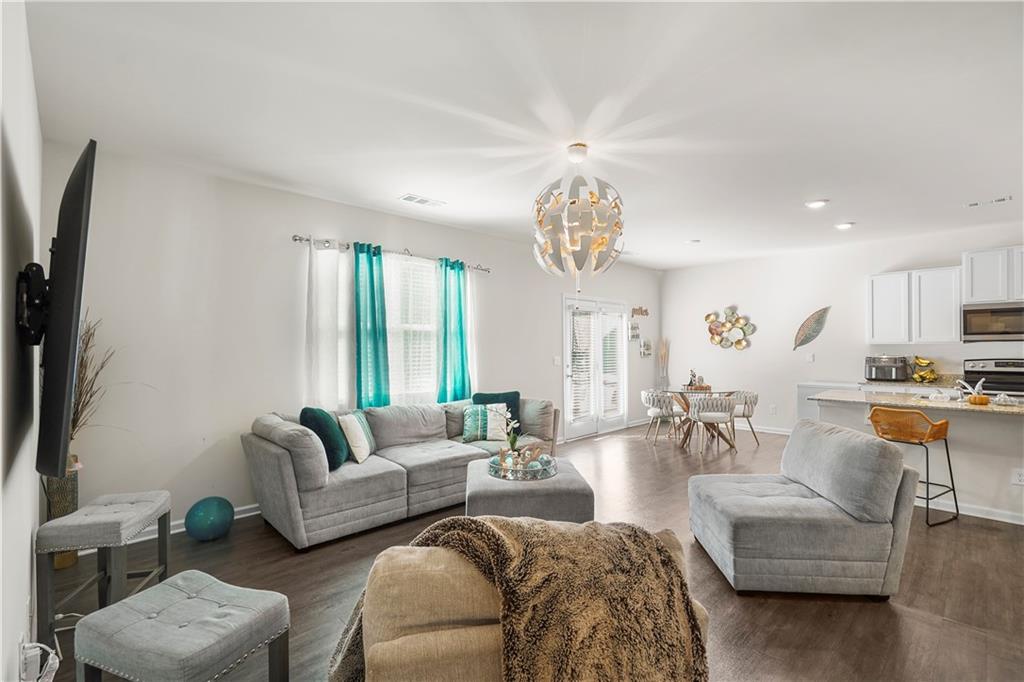 499 Walnut Grv Way Pendergrass, GA 30567 - Photo 11 of 19 a living room with furniture a chandelier and a flat screen tv