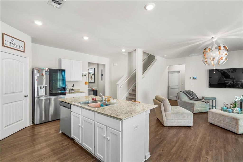 499 Walnut Grv Way Pendergrass, GA 30567 - Photo 2 of 19 a open kitchen with stainless steel appliances kitchen island granite countertop a refrigerator a stove a sink dishwasher and white countertops with wooden floor