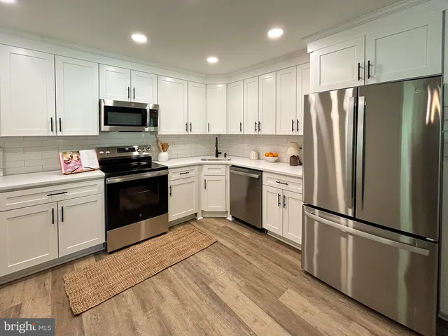 a kitchen with white cabinets stainless steel appliances and a refrigerator