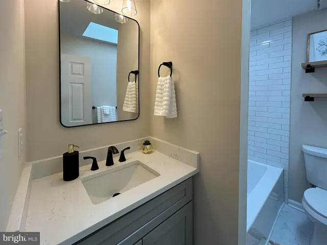 a bathroom with a sink vanity mirror and toilet