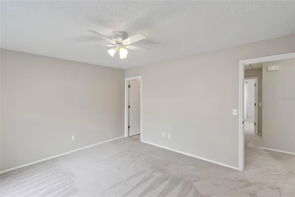 an empty room with a fan & a window