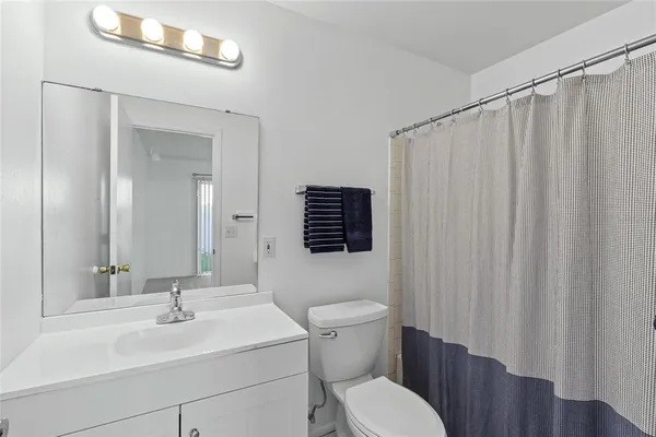 a bathroom with a sink a toilet a mirror and shower curtain