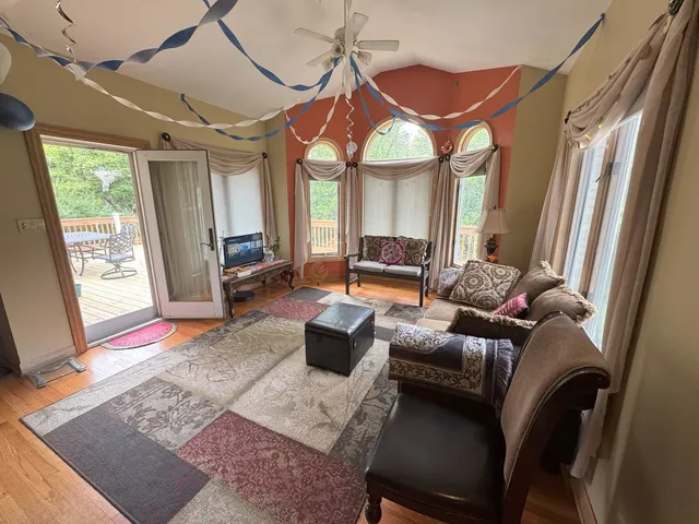 an empty room with chandelier fan and windows