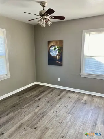 a view of an empty room with window and wooden floor
