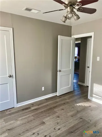 an empty room with wooden floor closet and windows