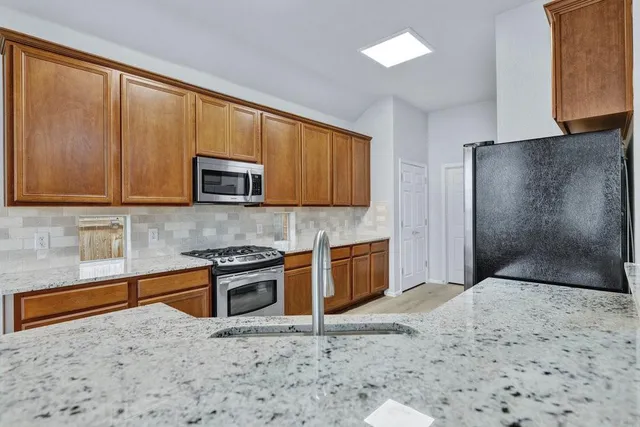 a kitchen with stainless steel appliances granite countertop a stove a sink and a microwave