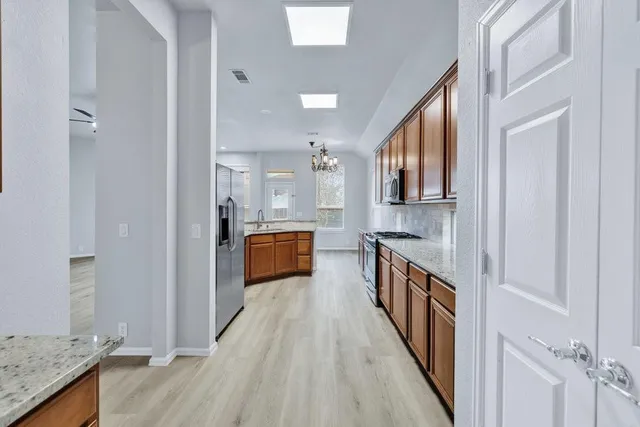 a kitchen with granite countertop a sink a counter top space and stainless steel appliances
