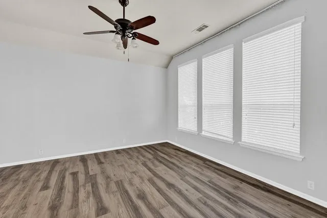 an empty room with windows and fan