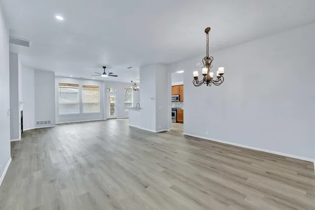 a view of a room with wooden floor chandelier and windows