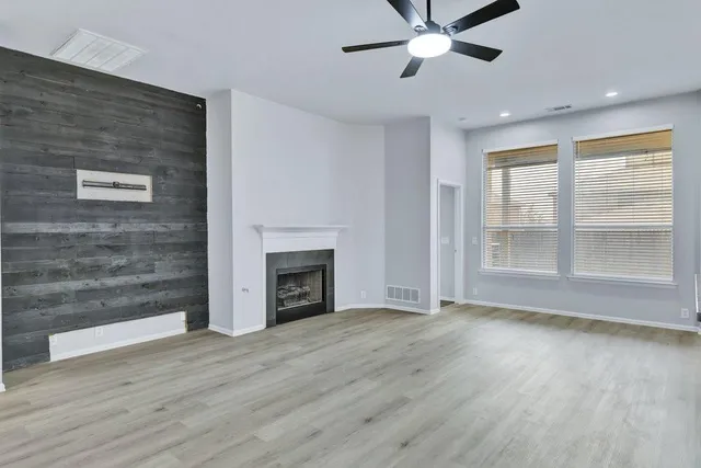 a view of an empty room with wooden floor fireplace and a window