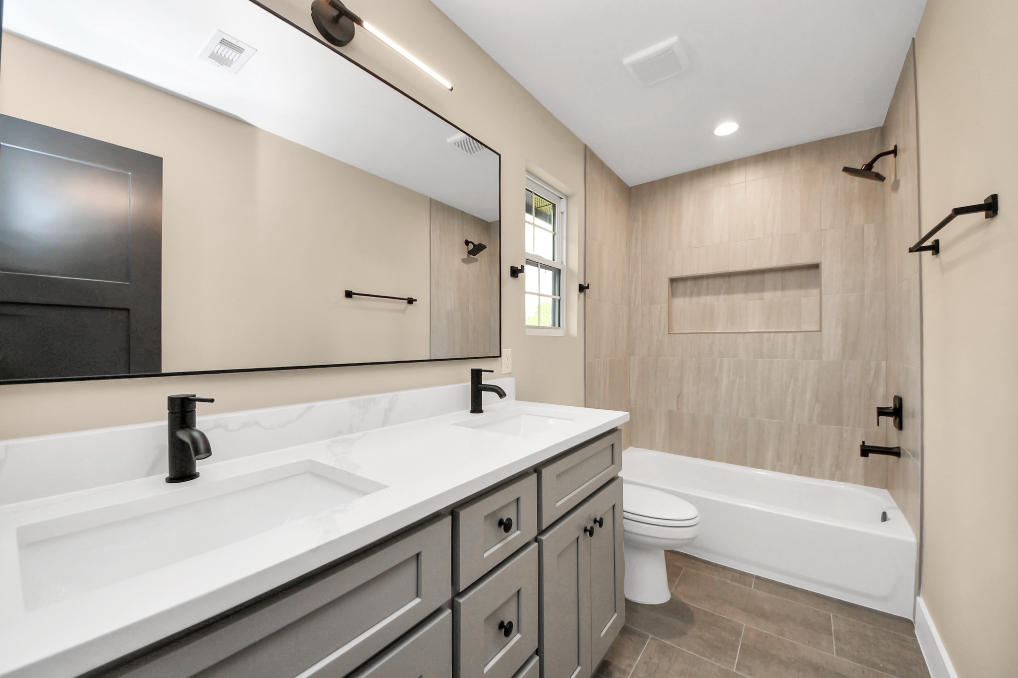 29727 Spring Forest Drive Spring, TX 77386 - Photo 30 of 37 Spacious secondary bathroom featuring a double-sink vanity, modern fixtures, and a tub/shower combo with designer tile surround and built-in niche.