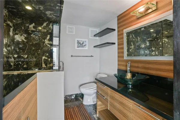 a bathroom with a sink a toilet a mirror and shower