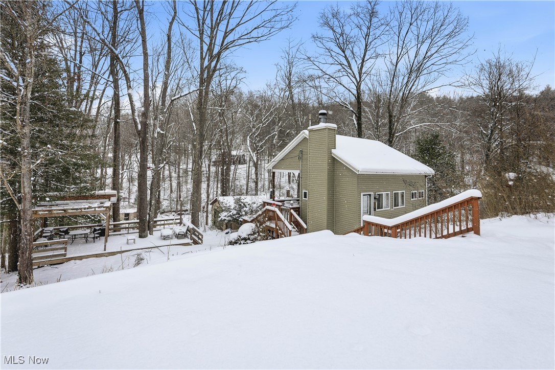 4254 Doral Road Southwest Carrollton, OH 44615 - Photo 3 of 46 Snow covered property featuring a deck, a chimney, and view of wooded area
