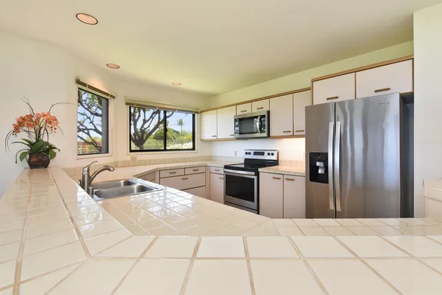 a kitchen with granite countertop a refrigerator and a stove top oven