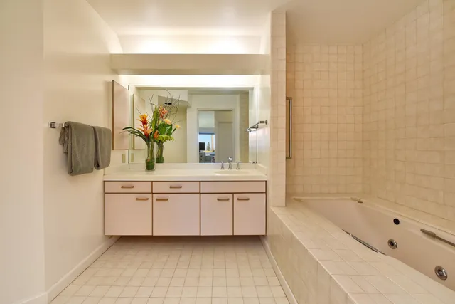 a spacious bathroom with a tub sink and mirror