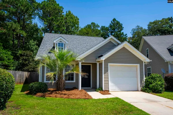 a view of a house with a yard plants and large tree