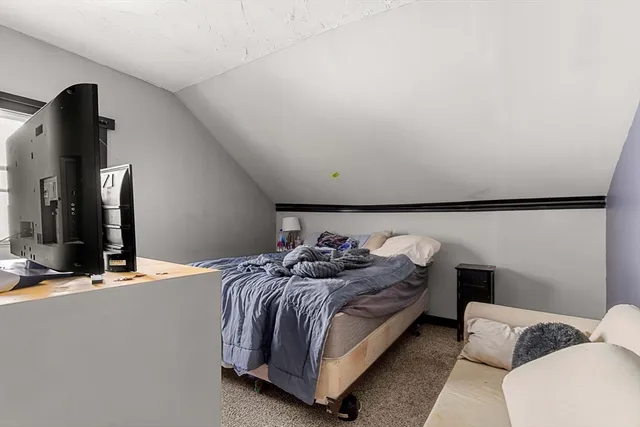 a bedroom with bed and a flat tv screen on dresser