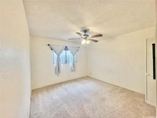 an empty room with a ceiling fan and glass door
