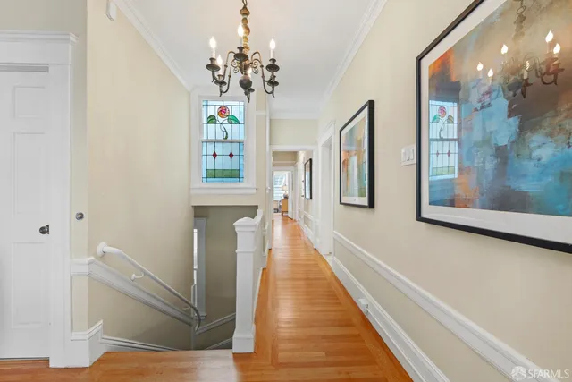 a view of a hallway with wooden floor and a bathroom