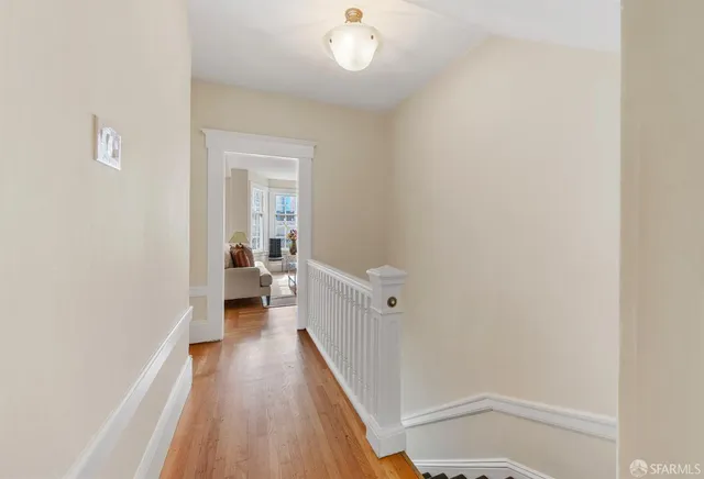 a view of a hallway with wooden floor and a bathroom