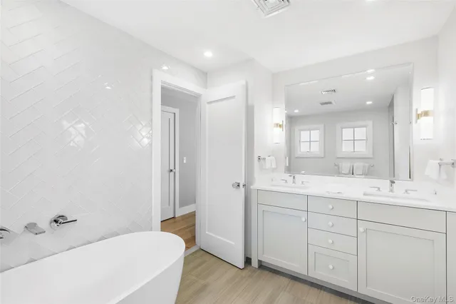 a spacious bathroom with a double vanity sink a mirror and a bathtub