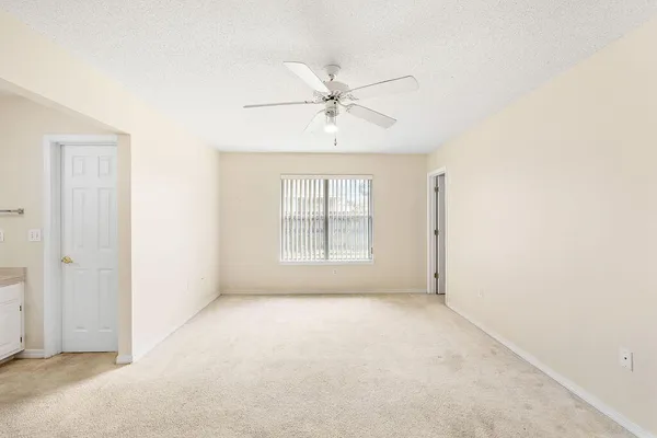 an empty room with chandelier fan and windows