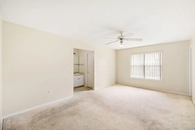 an empty room with a ceiling fan and window