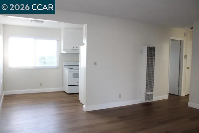 a view of empty room with wooden floor and window