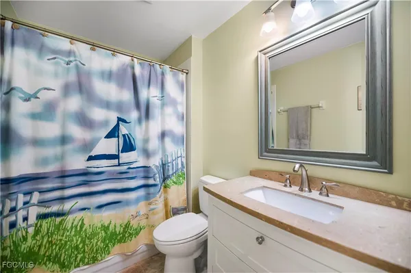 a bathroom with a granite countertop sink a toilet and a mirror