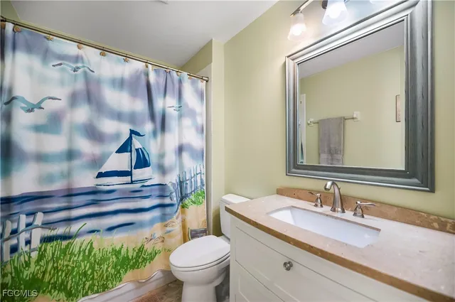 a bathroom with a granite countertop sink a toilet and a mirror