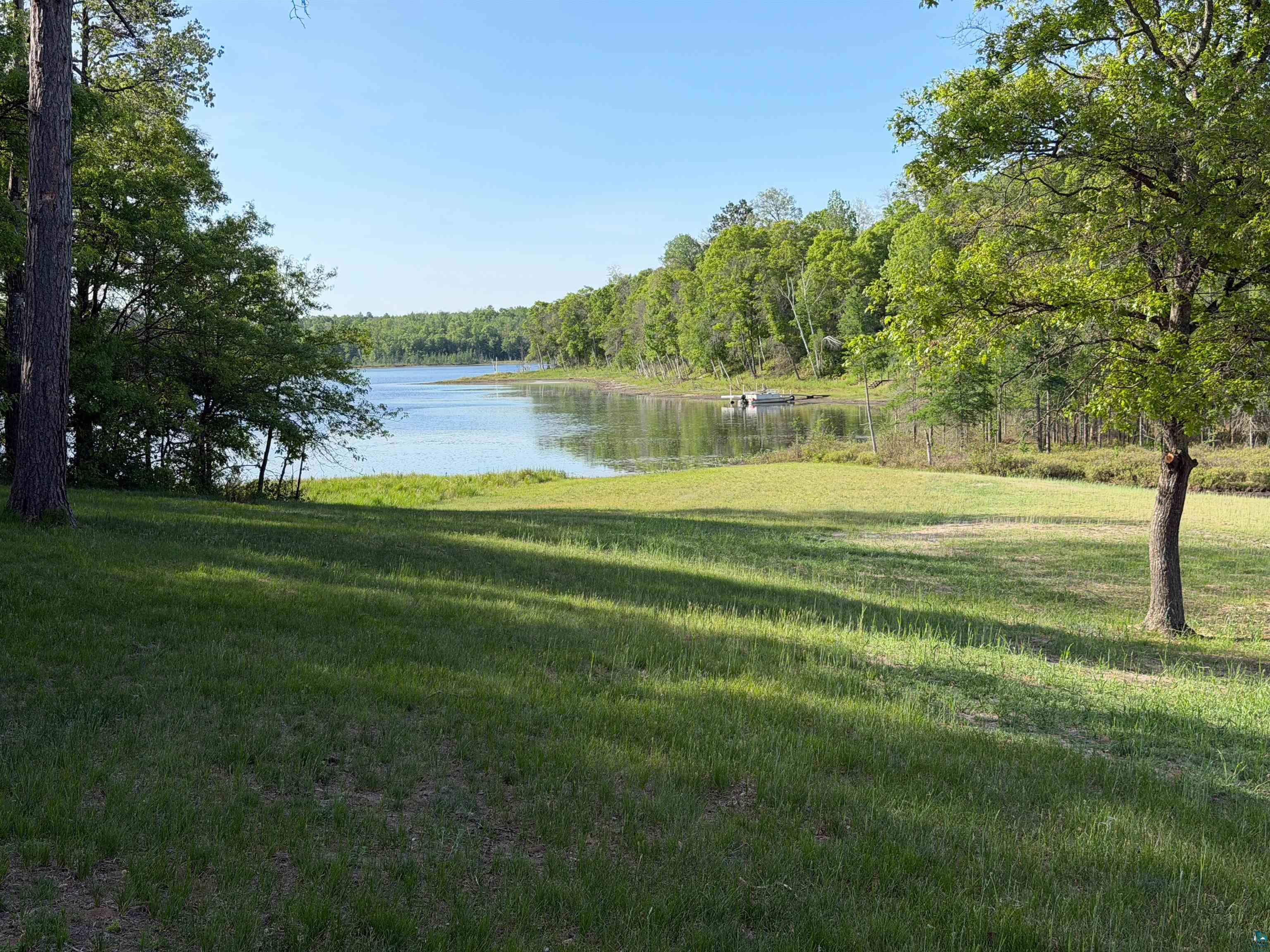11702 East Mail Road Gordon, WI 54838 - Photo 31 of 60 Expansive waterfront property featuring a large grassy lawn, mature trees, and direct water access