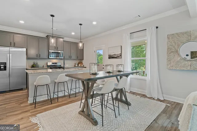 a kitchen with stainless steel appliances granite countertop a sink a stove a refrigerator cabinets and chairs